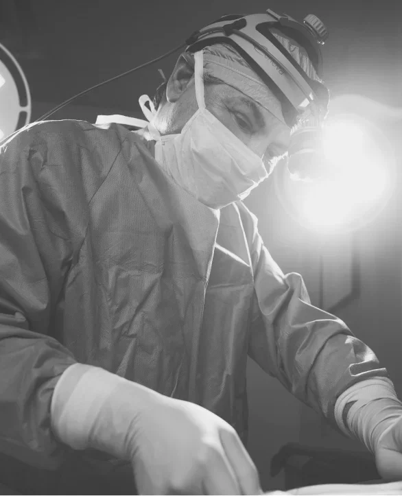Doctor James Michael Conkright MD performing operation in sterile gown and headlamp in black and white photograph - in Evansville, IN